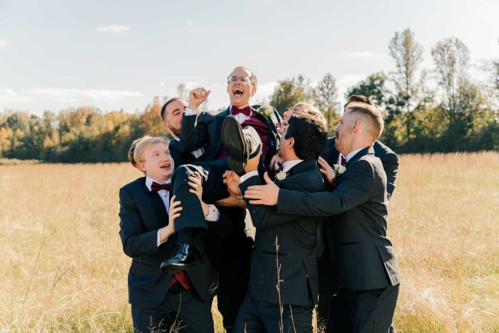 Groomsmen hold up groom at Plein Air